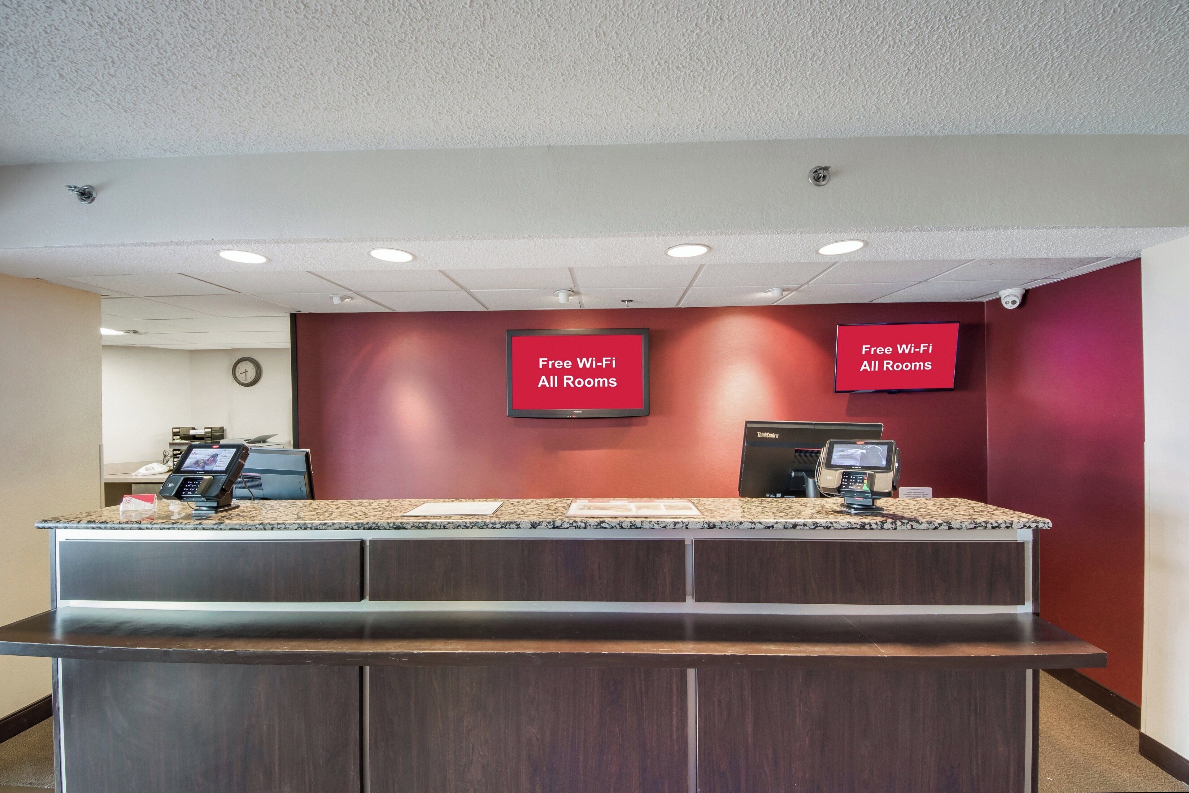 A reception desk with a digital display, a clock, and a sign indicating free Wi-Fi in all rooms.