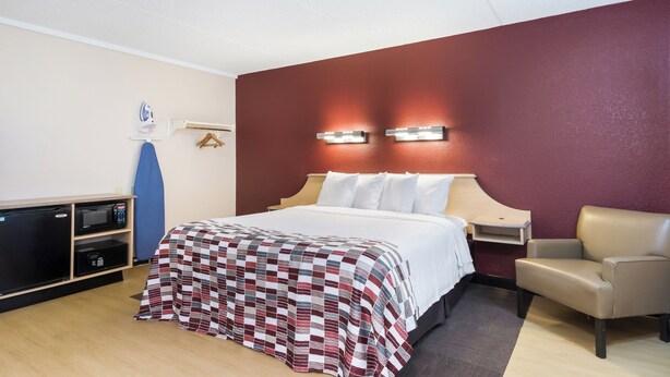 Quarto de hotel com cama, escrivaninha, cadeira e micro-ondas.