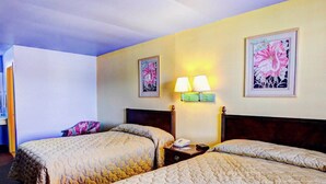 A hotel room with two beds, a nightstand with a lamp, and two framed floral paintings on the wall. - Nites Inn (Killeen)
