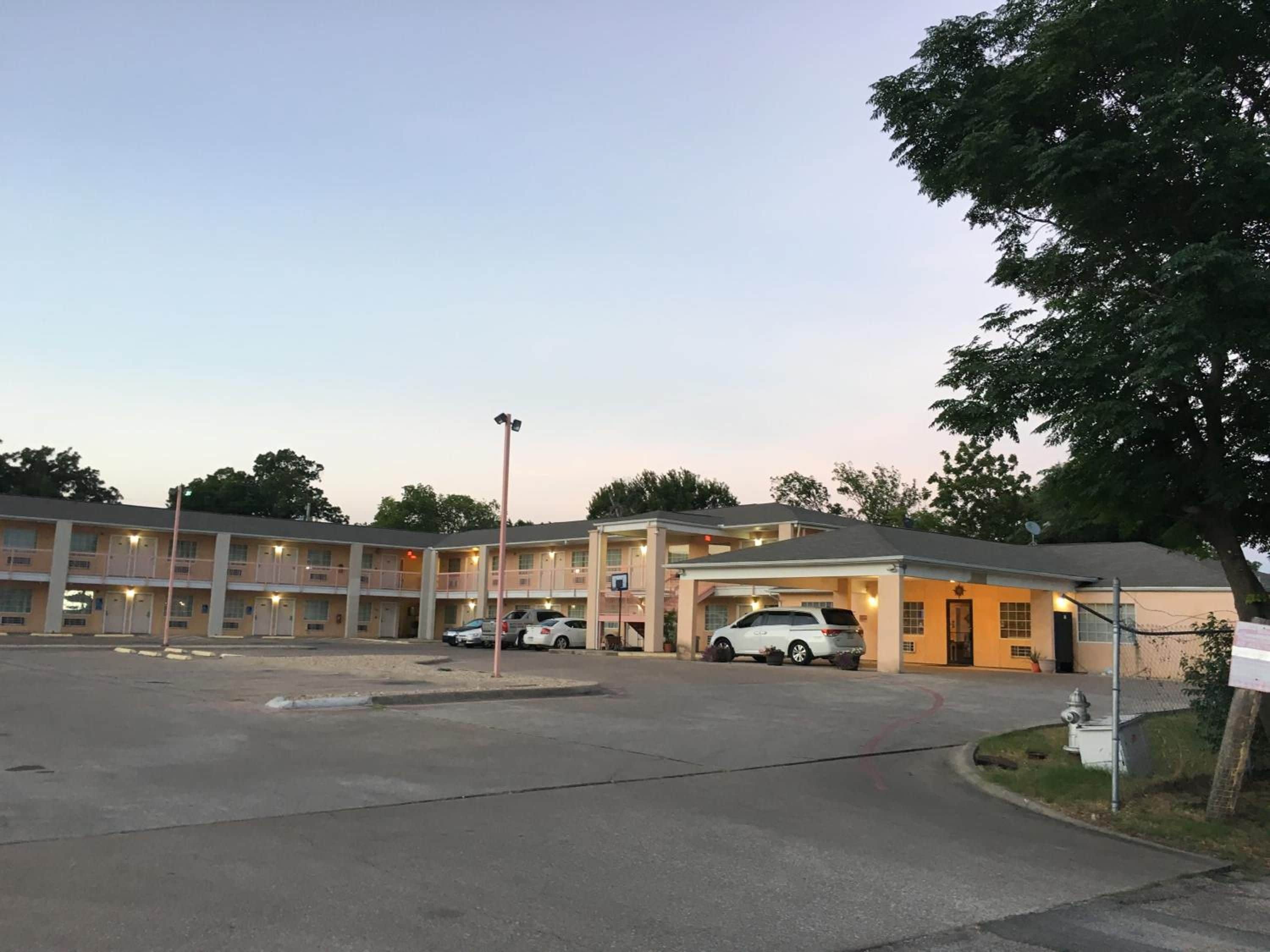 Ein mehrstöckiges Motel mit Parkplatz und überdachtem Parkbereich.
