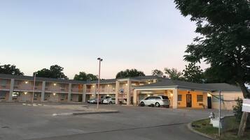 A multi-story motel with a parking lot and a covered parking area.