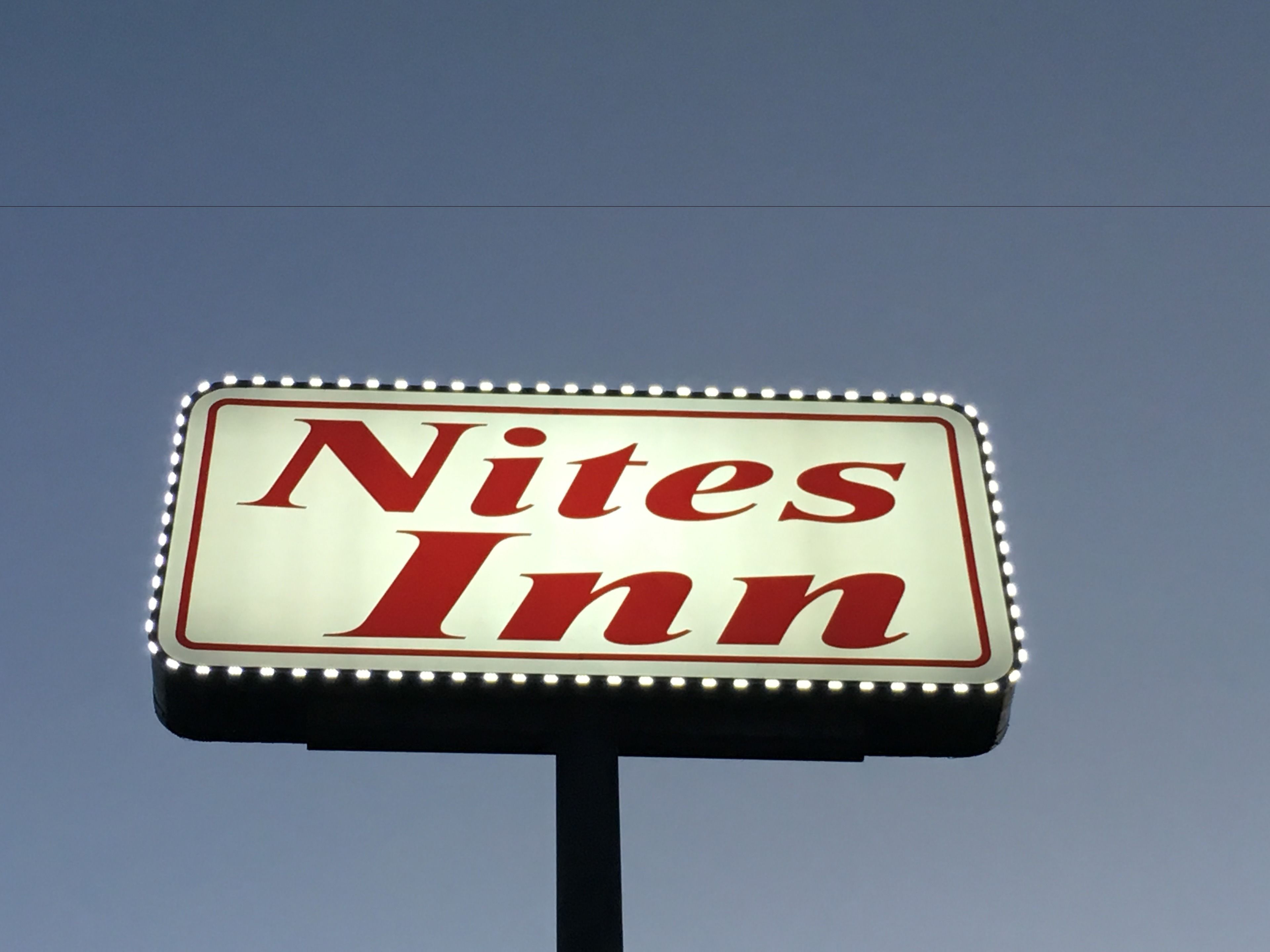 A sign for Nites Inn with a clear sky background.