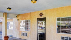 A building entrance with a door, windows, and a sun emblem. - Nites Inn (Killeen)