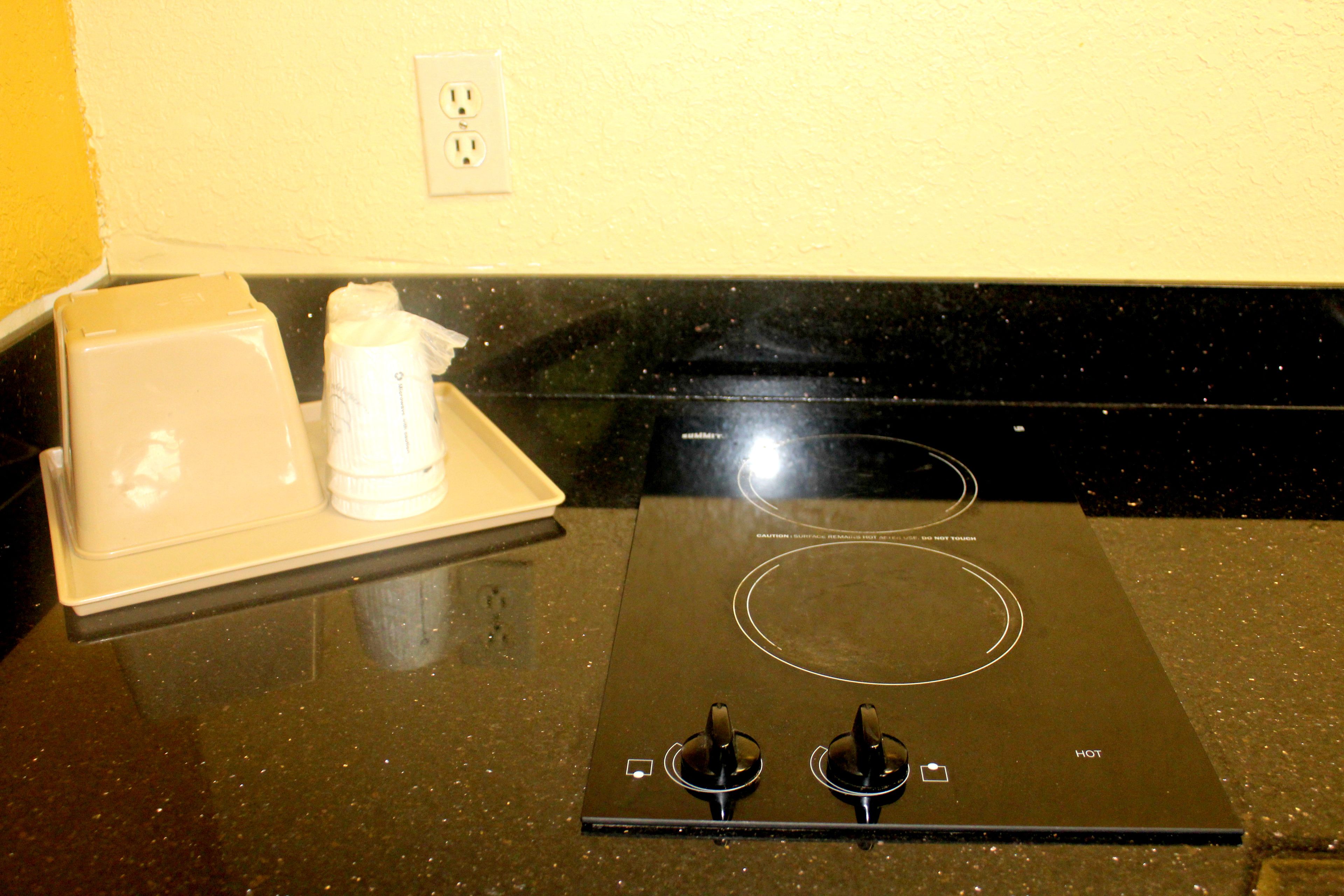 A kitchen with an induction cooktop, a white appliance on the counter, and a wall socket.