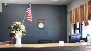 A reception desk with an American flag, a clock, and a sign indicating manager on duty. - Village Inn Cotulla (Cotulla)