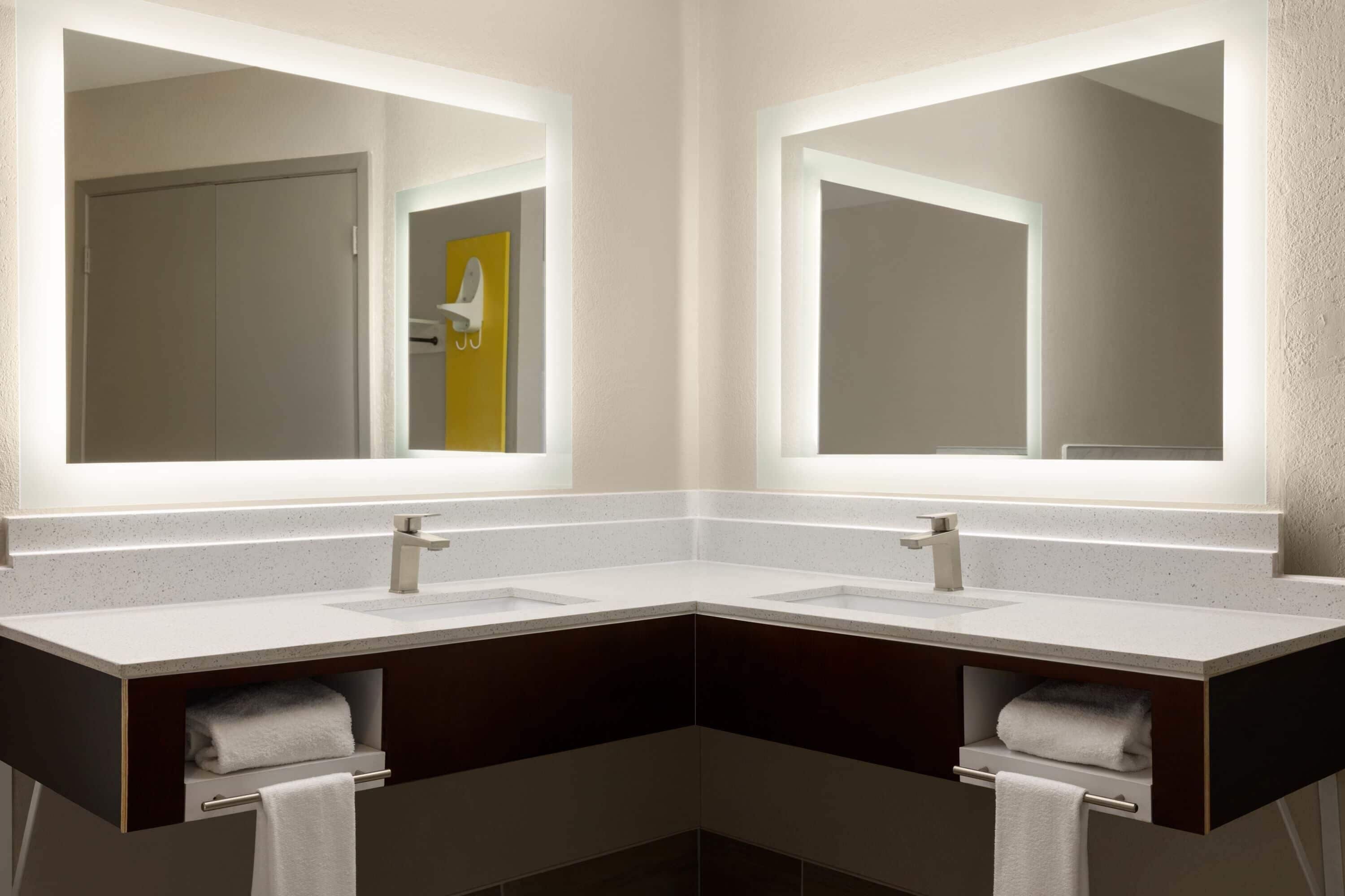 Une salle de bain moderne avec deux lavabos, des meubles de rangement aux couleurs sombres et de grands miroirs.