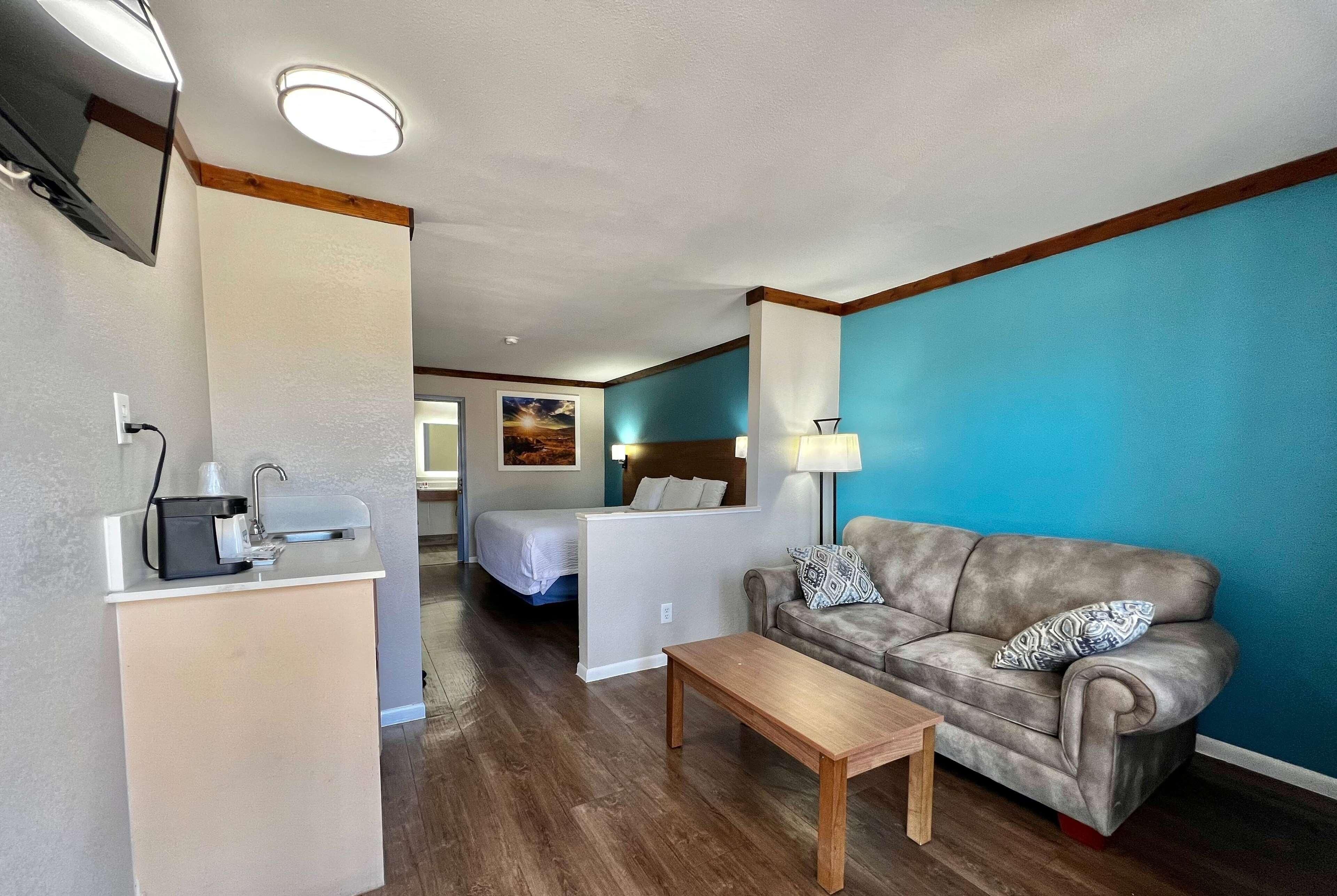 Ett hotellrum med en säng, en soffa, en kaffemaskin och ett skrivbord.