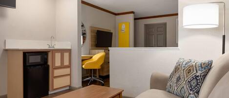 A compact living space with a kitchenette, a dining area, and a seating area with a patterned pillow.