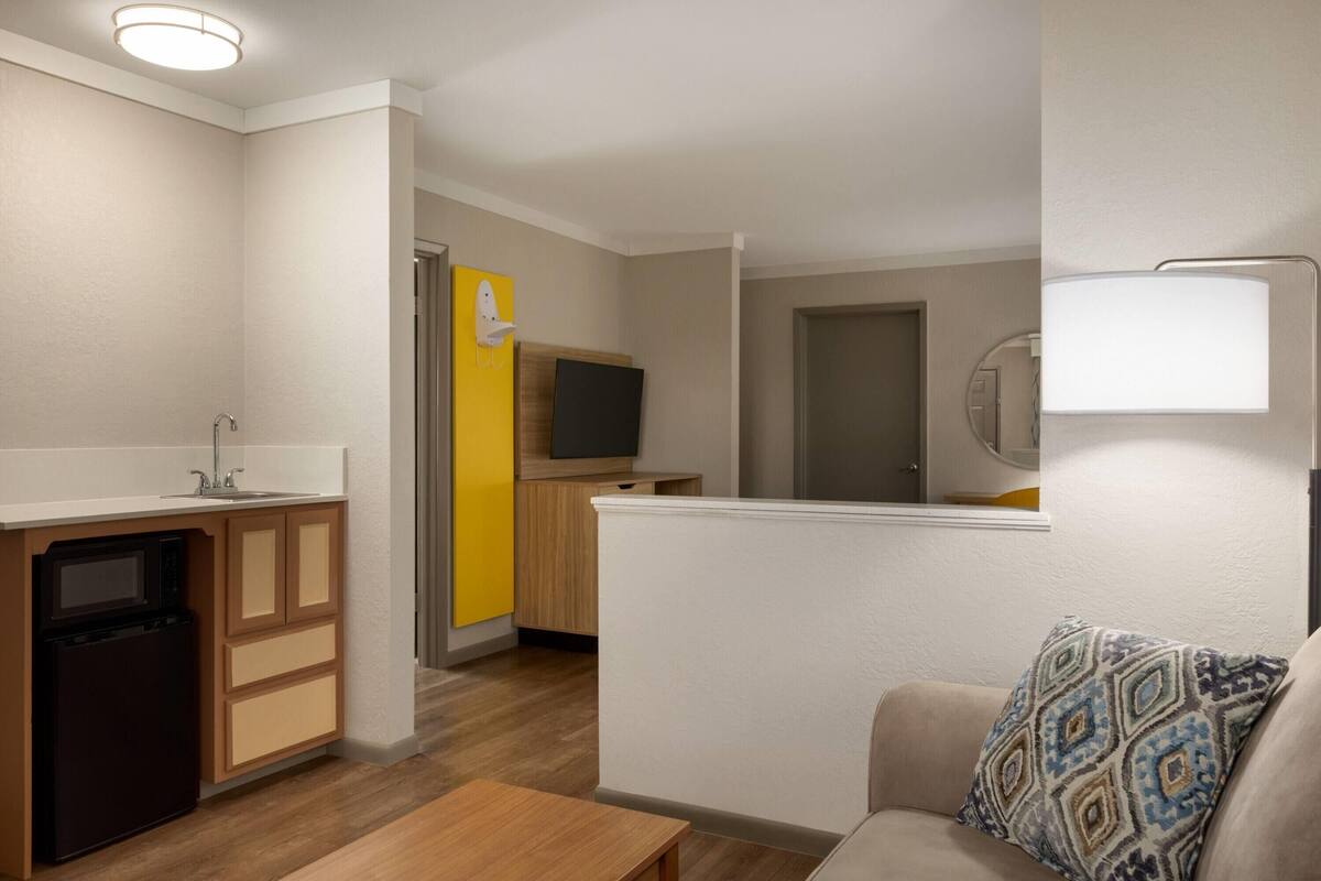 A compact living space with a kitchenette, a sofa, and a television.