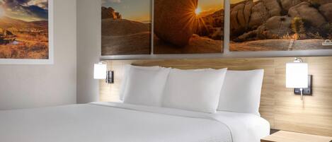 Habitación de hotel con una cama grande, dos mesitas de noche y tres cuadros enmarcados en la pared.