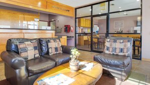 A lobby with leather sofas, a wooden registration desk, and a view into the kitchen area.