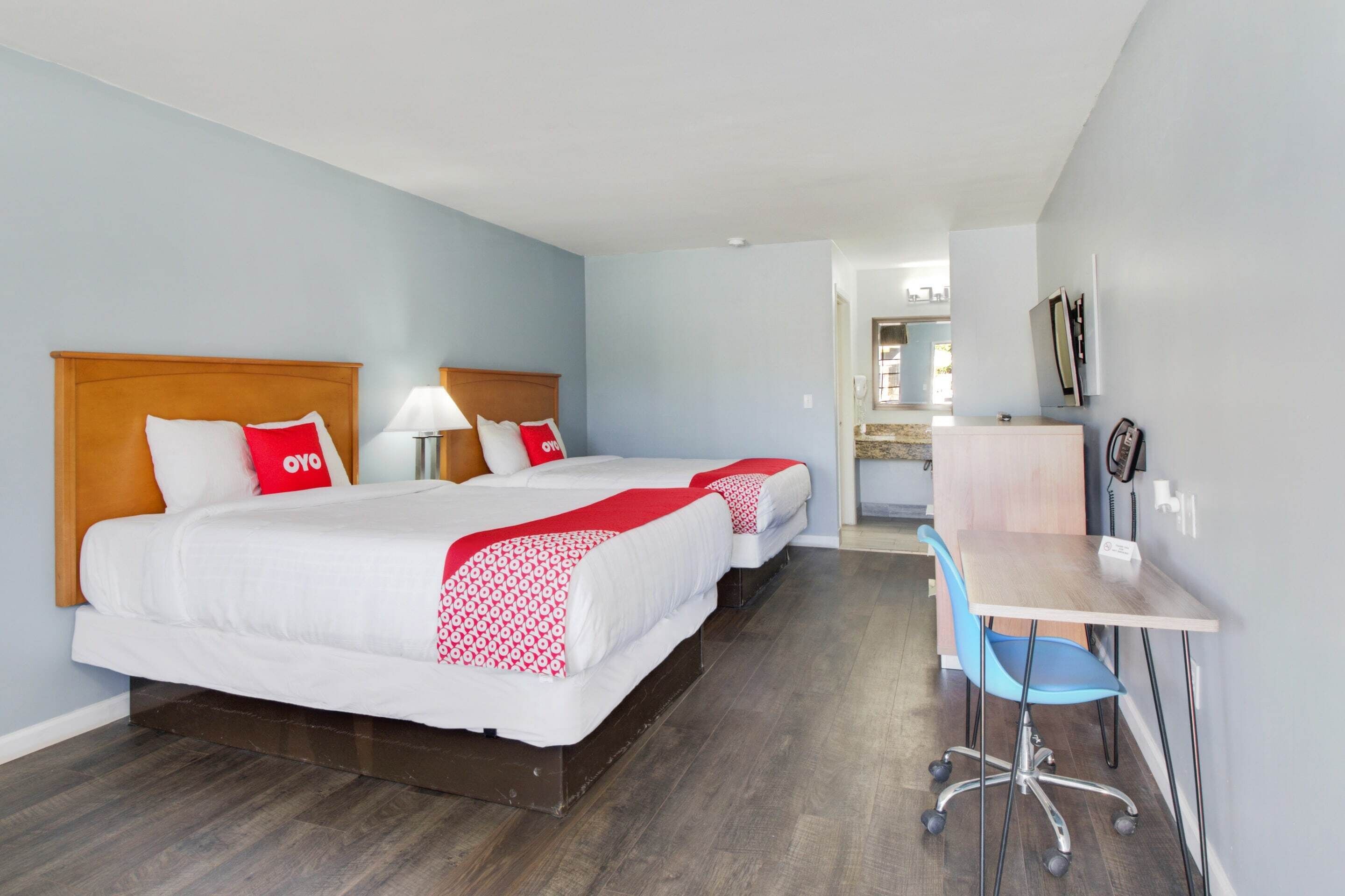 A hotel room with two beds, a desk, and a chair.