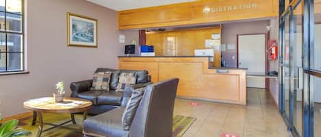 A reception area with a registration desk, a couch, a coffee table, and a potted plant.