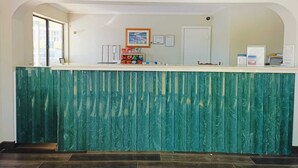 A reception desk with a green marble-like counter, framed artwork on the wall, and a door to the right.