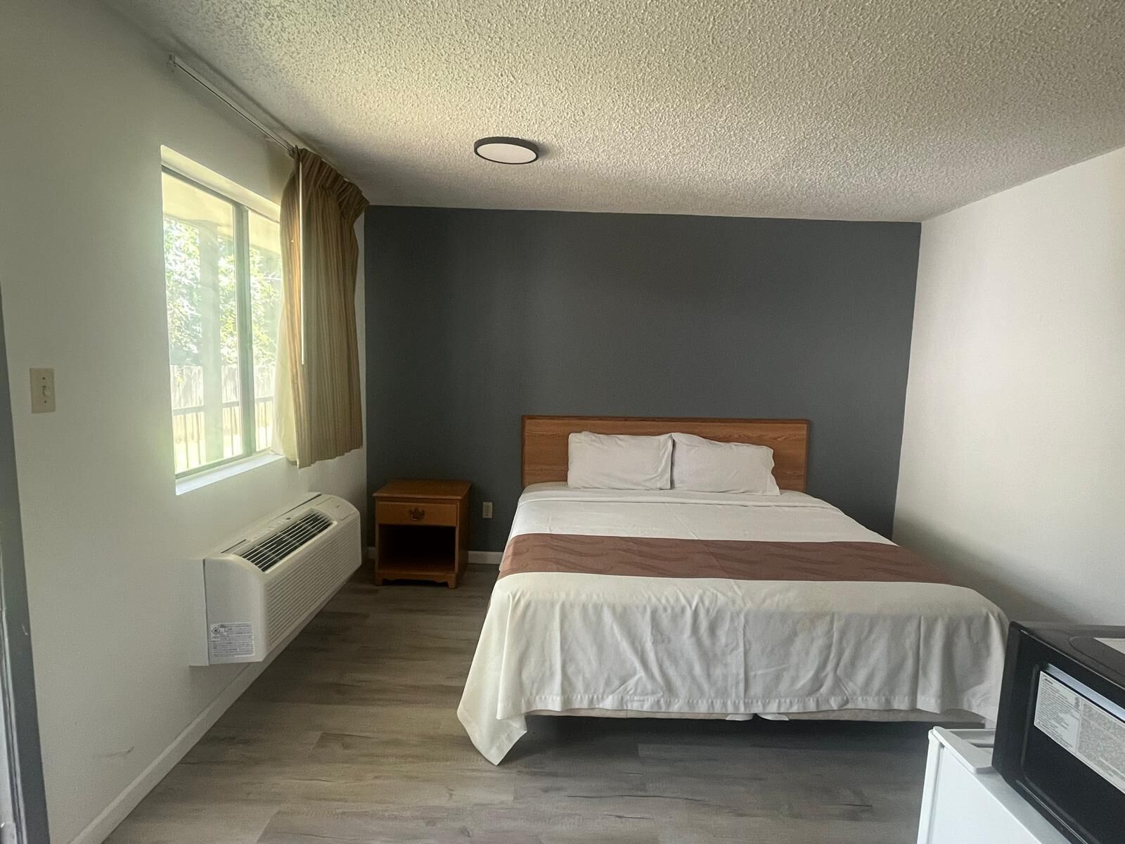 A bedroom with a bed, a nightstand, a heater, and a window.