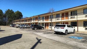 A row of motel buildings with multiple parking spaces, a handicap parking sign, and a clear blue sky.