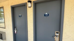 Two grey doors with numbers 105 and 103, a small light above the left door, and a metal handle on both doors.
