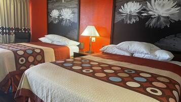 Habitación de hotel con dos camas, una mesita de noche con lámpara y dos grandes cuadros con motivos florales.