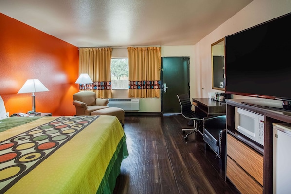 A hotel room with a bed, desk, chair, TV, and kitchenette. - Super 8 by Wyndham Giddings (Giddings)