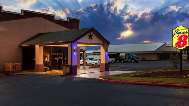 A hotel entrance with a covered waiting area and a visible Super 8 sign. - Super 8 by Wyndham Giddings (Giddings)