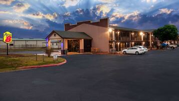 A motel with a Super 8 sign, a parking lot, and a white car parked in front.