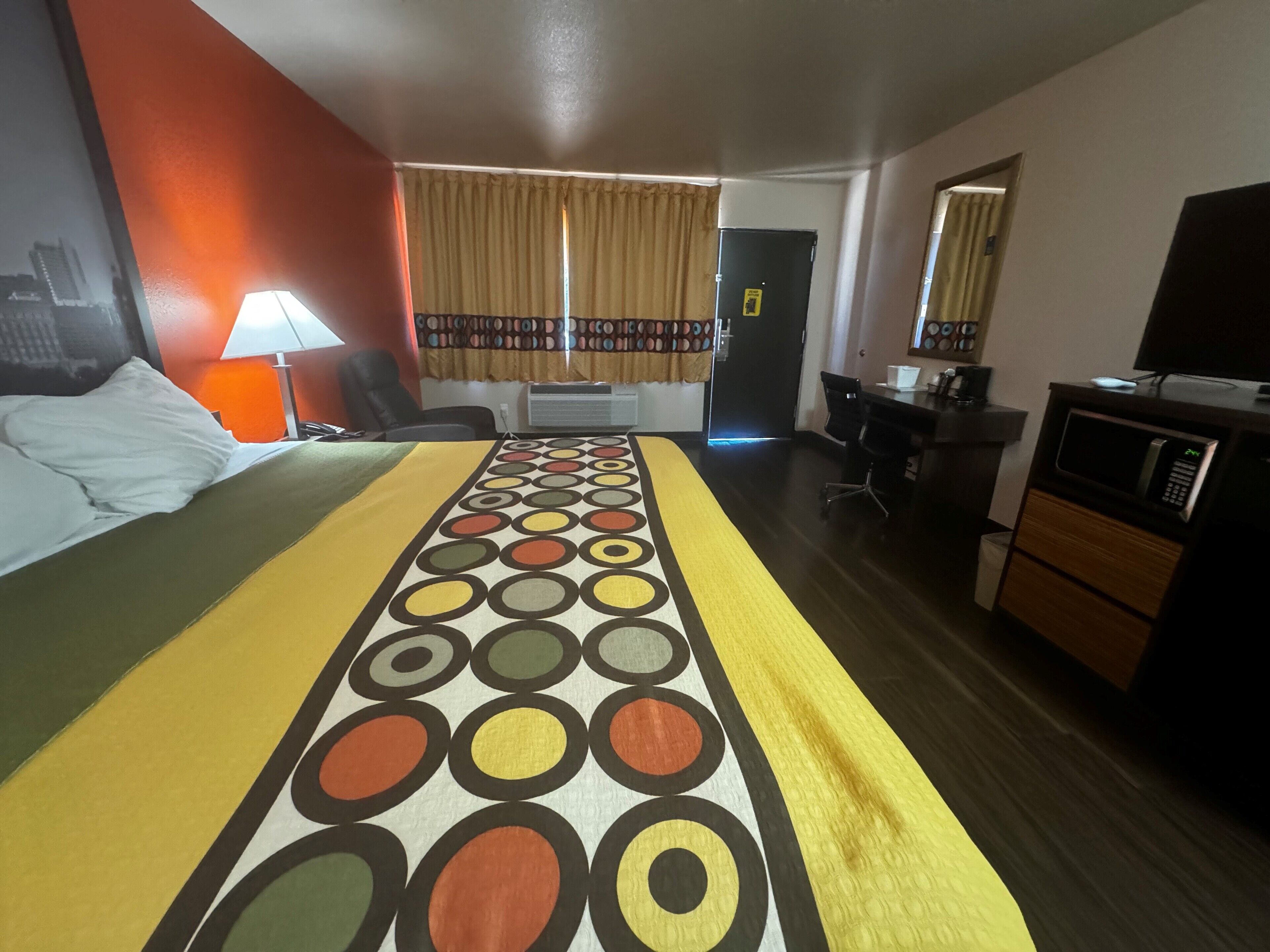 A hotel room with a bed, a desk, a chair, a television, and a microwave.