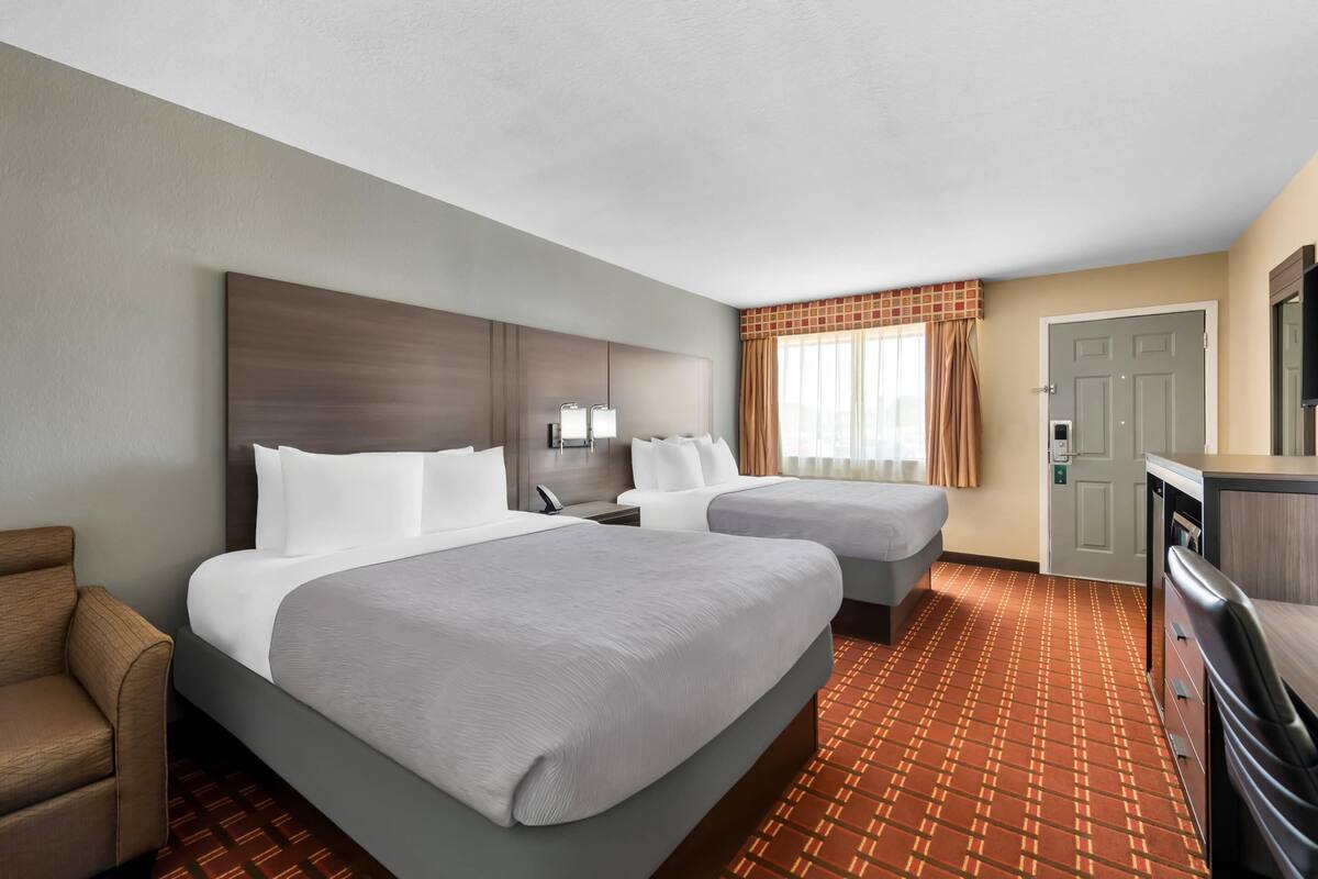 Ein Hotelzimmer mit zwei Betten, einem Schreibtisch, einem Stuhl und einem Fernseher.