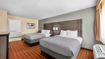 Habitación de hotel con dos camas, un escritorio y una ventana con cortinas.