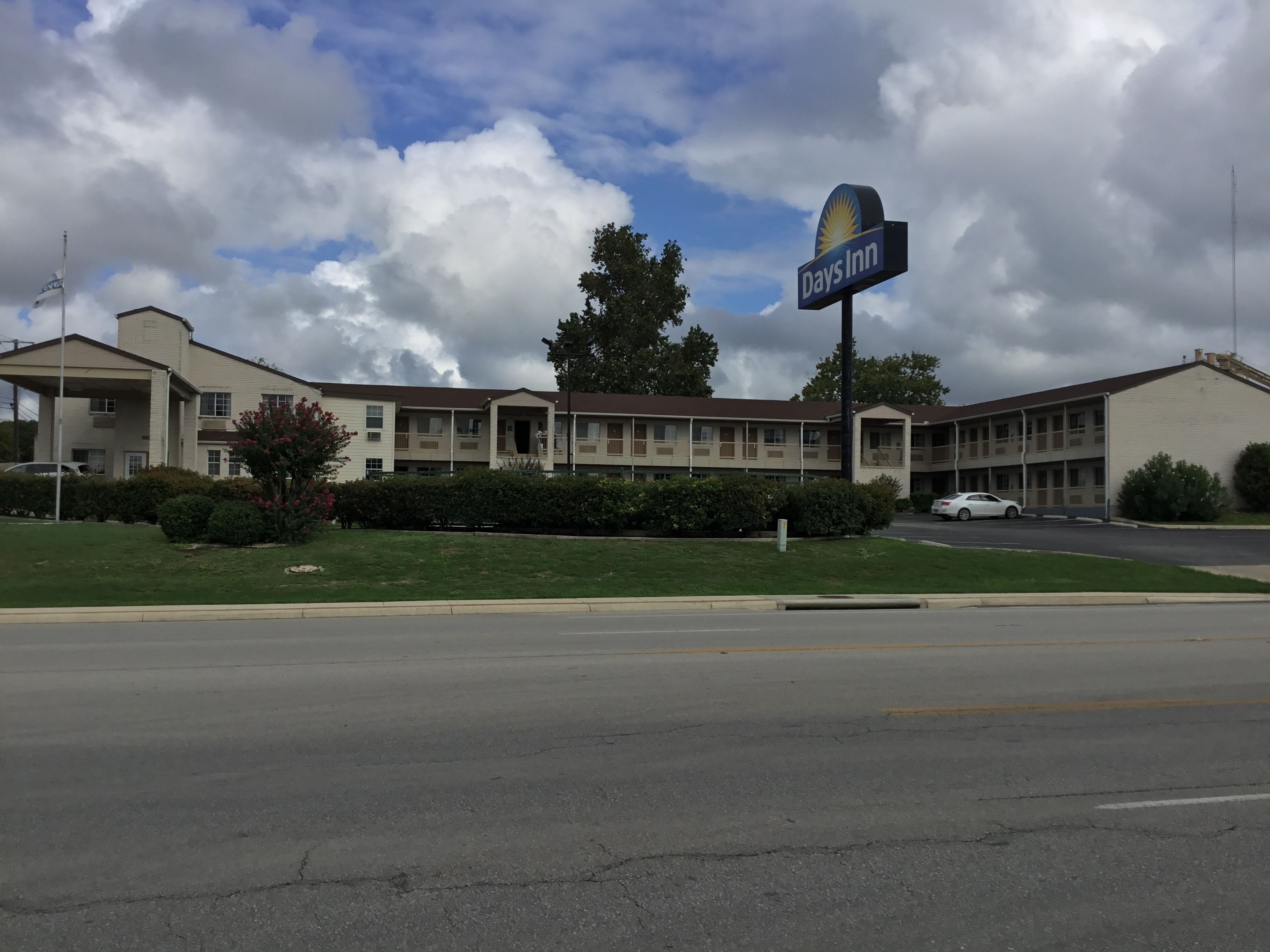 A Days Inn with a two-story building, a parking lot, and a grassy area with bushes.