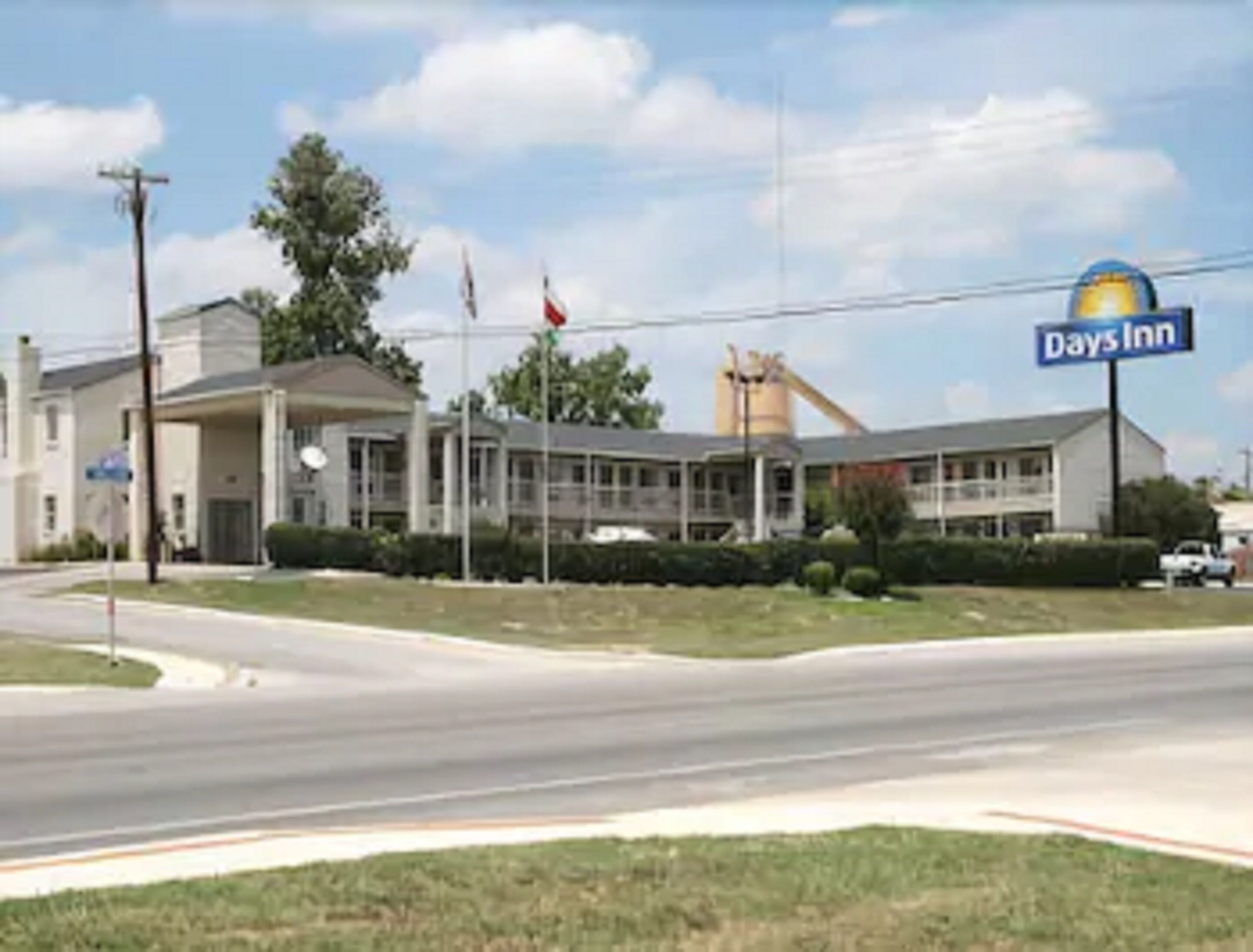 A Days Inn hotel with a large parking lot, a flagpole, and a clear sky.
