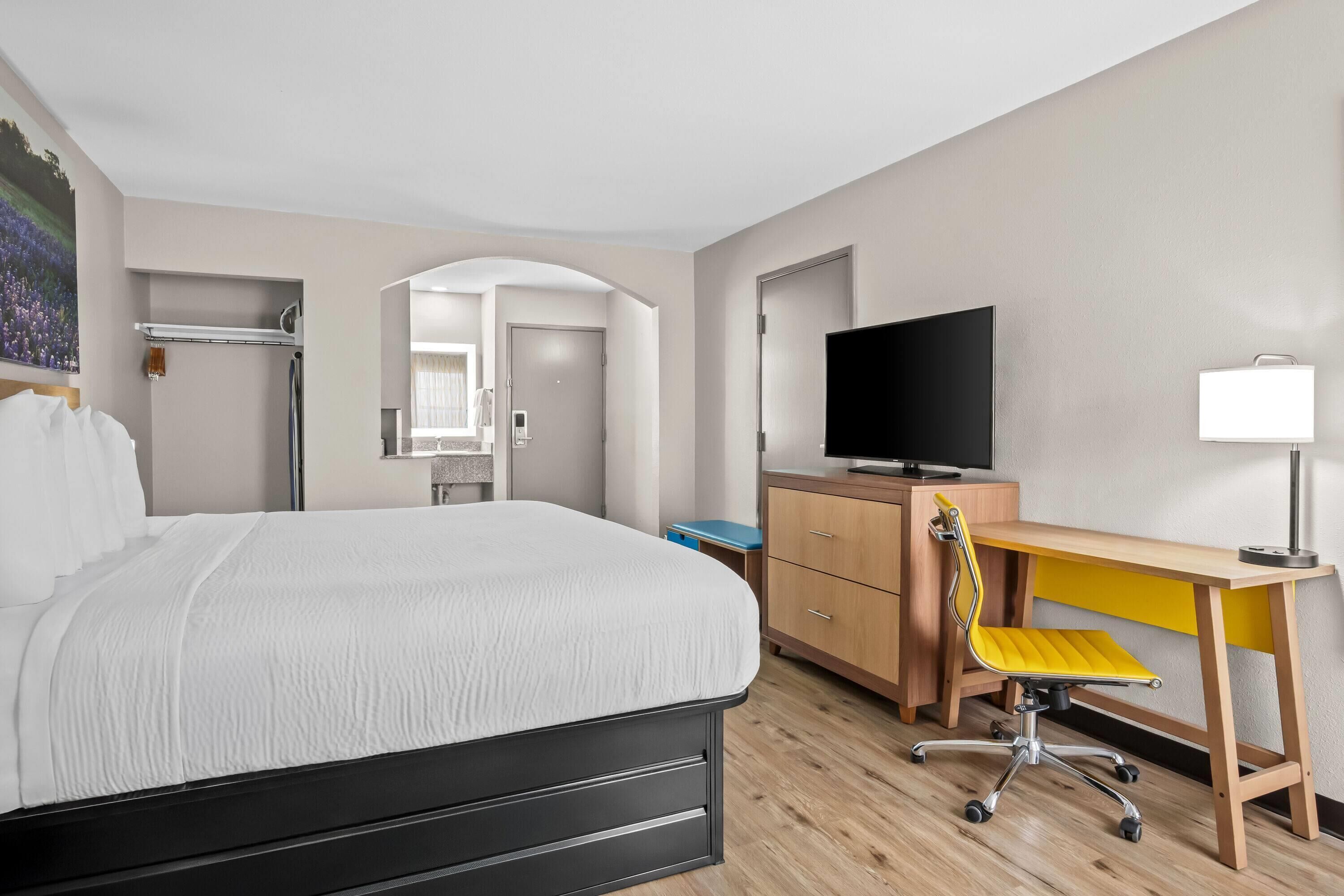 Une chambre d’hôtel comprenant un lit, un bureau avec une chaise, une télévision et un miroir.