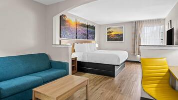 Una habitación de hotel moderna con una cama, un sofá, un escritorio y obras de arte en las paredes.