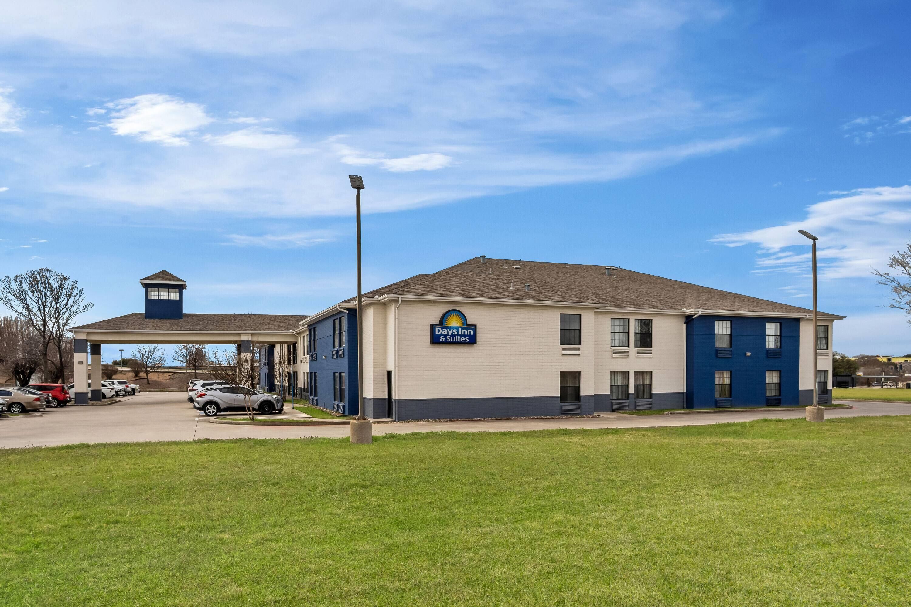 A Days Inn & Suites building with a parking lot and a small tower structure.