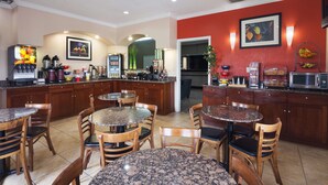 Una cocina de hotel con encimeras de granito, armarios de madera y una pared de acento roja.