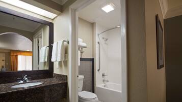 Une salle de bain comprenant un lavabo avec un plan de toilette en granit, des toilettes, une baignoire et une douche.