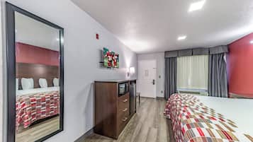 Una habitación de hotel con dos camas, televisión, cómoda y ventana con cortinas.
