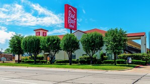A Red Roof Inn with a prominent red sign, surrounded by well-maintained greenery and a clear blue sky. - Red Roof Inn Dallas - Mesquite/ Fair Park NE (Mesquite)