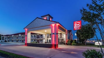 Un Red Roof Inn de dos pisos, con un área de estar cubierta al aire libre y una entrada visible.