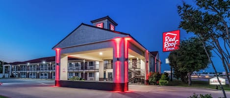 A Red Roof Inn with a two-story structure, a covered outdoor seating area, and a visible entrance.