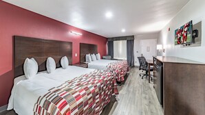 A hotel room with two beds, a desk, a chair, and a TV mounted on the wall.