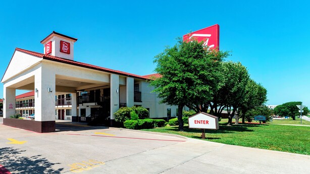 A building with a red roof, a large red sign, and an 'ENTER' sign. - Red Roof Inn Dallas - Mesquite/ Fair Park NE (Mesquite)