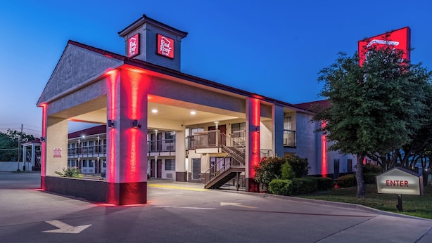 A Red Roof Inn with a covered entrance, outdoor seating area, and a staircase leading to the upper level.