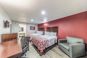 Habitación de hotel con dos camas, un escritorio, una silla y un sofá.
