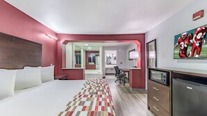 A hotel room with a bed, a desk, a mirror, a television, and a microwave. - Red Roof Inn Dallas - Mesquite/ Fair Park NE (Mesquite)