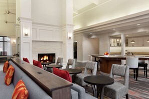 A modern hotel lobby with a fireplace, seating area, and a bar. - Homewood Suites by Hilton North Dallas-Plano (Plano)