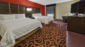 Une chambre d’h ôtel avec deux lits, un bureau, une télévision et une moquette à motifs.