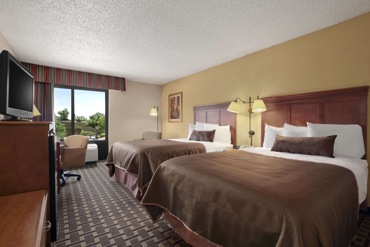 Une chambre d’hôtel avec deux lits, une télévision, un bureau et une chaise.