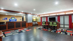 A Days Inn & Suites lobby with a reception desk, seating area, and a television. - Days Inn & Suites by Wyndham Tyler (Tyler)