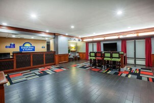 Hall del Days Inn & Suites con una recepción, zona de estar y televisor.