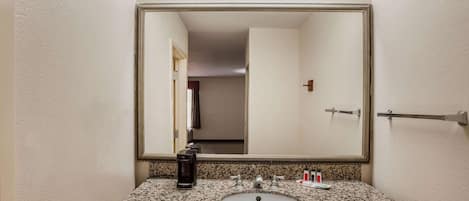 A bathroom with a granite countertop, a sink, a mirror, and a towel rack.